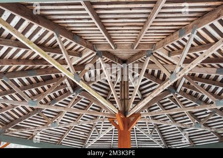 Teil der Holzdachkonstruktion auf dem Pavillon. Das Innendach einer hölzernen Gartenlaube, die von innen nach oben und nach außen blickt. Niemand, selektiver Fokus Stockfoto