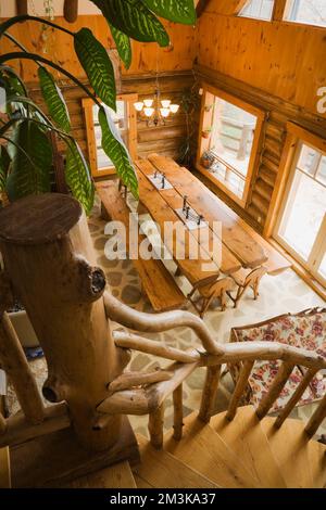 Blick von oben auf einen geteilten Holztisch und Bänke im Speisesaal in einer rustikalen Blockhütte. Stockfoto