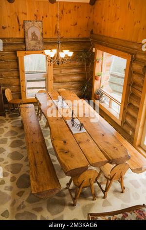 Blick von oben auf einen geteilten Holztisch und Bänke im Speisesaal in einer rustikalen Blockhütte. Stockfoto