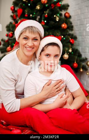 Fröhliche Mutter und Kind, die mit weihnachtsbaumschmuck spielen. Stockfoto