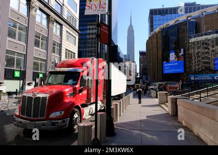 Ein roter Parkplatz für Sattelanhänger in der West 33. Street mit Madison Square Garden und Empire State Building im Hintergrund.Midtown Manhattan.New York City.USA Stockfoto