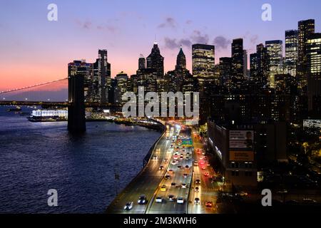 Blick auf die Brooklyn Bridge in der Dämmerung über den East River mit FDR Drive und der Skyline von Lower Manhattan im Hintergrund. New York City.USA Stockfoto