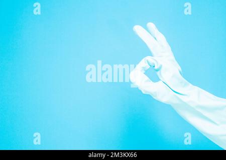 Reinigungskonzept, Hand in medizinische Handschuhe mit „Doing ok“-Symbol isoliert auf hellblauem Hintergrund. Stockfoto