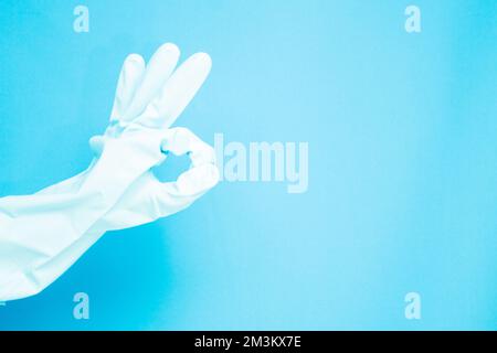 Reinigungskonzept, Hand in medizinische Handschuhe mit „Doing ok“-Symbol isoliert auf hellblauem Hintergrund. Stockfoto