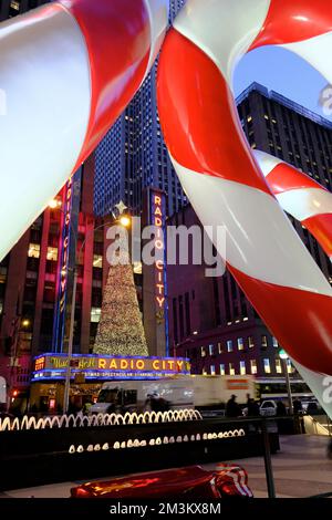 Riesige Zuckerstangen als Weihnachtsdekoration mit Radio City Music Hall und 6. Avenue im Hintergrund. Midtown Manhattan. New York City. USA Stockfoto