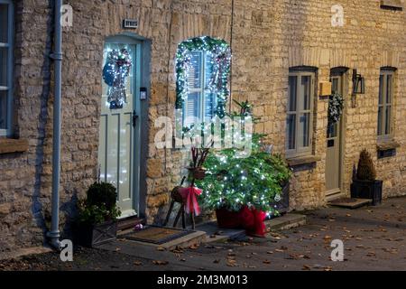 Weihnachtsdekorationen vor einer Hütte bei Nacht. Stow on the Wold, Cotswolds, Gloucestershire, England Stockfoto