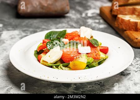 Salat mit Lachs, Schafskäse, Kräutern und Tomaten. Mediterrane Diät. Leckere und gesunde Speisenrezepte. Nahaufnahme Stockfoto