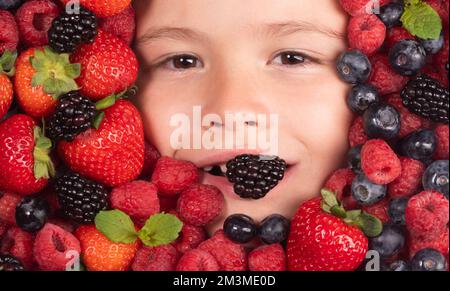 Beeren mit Kindern sehen aus der Nahaufnahme. Draufsicht des Kindergesichts mit berri. Beere in der Nähe des Kindergesichts. Süßer kleiner Junge isst Beeren. Ein Kind isst Vitamine. Schließen Stockfoto