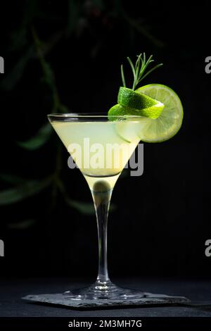 Alkoholischer Gimlet-Cocktail mit trockenem Gin, Likör, Limettensaft und Eis in Glas, garniert mit Limettenschale. Schwarzer Hintergrund Stockfoto