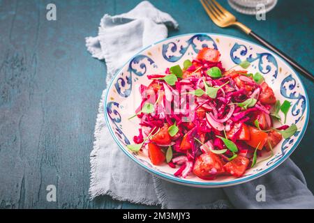 Wintersalat: Eingelegter Rotkohlsalat mit Rettich, Tomaten, Zwiebeln und Winterportulak. Vegetarisches gesundes Essen. Stockfoto