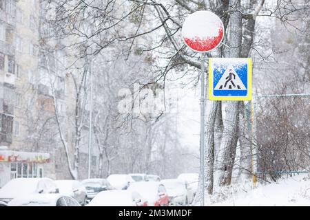 Schwierige Straßenverhältnisse – Straße im Winter Schneefall mit schneebedeckten Fußgängerschildern Stockfoto