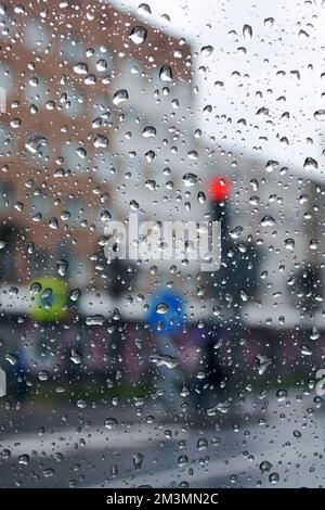 Regentropfen auf der Windschutzscheibe auf Stadtstraße Hintergrund Makrofotografie Stockfoto