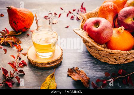Herbstzusammensetzung mit Kürbissen, Herbstblättern, roten Äpfeln und Apfelwein Stockfoto