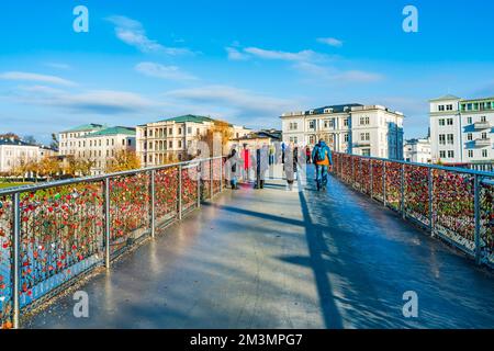 SALZBURG, AUSTIRA - 06. DEZEMBER 2022: Touristen gehen auf der Makartsteg-Brücke (Love Locks Bridge) über die Salzach im historischen Stadtzentrum Stockfoto