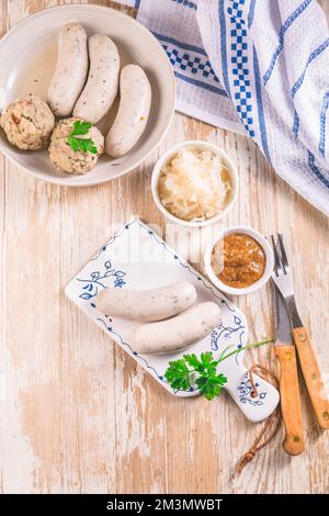 Traditionelle bayerische Küche - Weiße Kalbswurst mit eingelegtem Weißkohl (Sauerkraut) und Brotknödeln mit Senfsauce Stockfoto