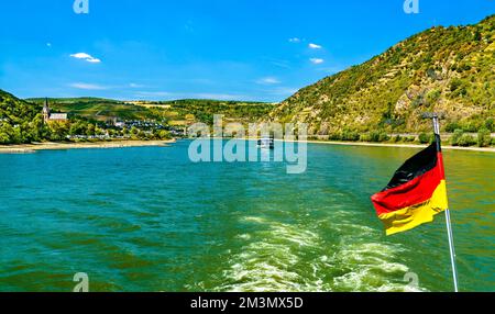 Deutsche Flagge auf einem Kreuzfahrtschiff in der Rheinschlucht. UNESCO-Weltkulturerbe in Deutschland Stockfoto