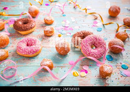 Traditioneller Berliner für Fasching und Party. Deutsch Krapfen oder Donuts mit Streamer und Konfetti. Bunte Karneval oder Geburtstag Bild Stockfoto