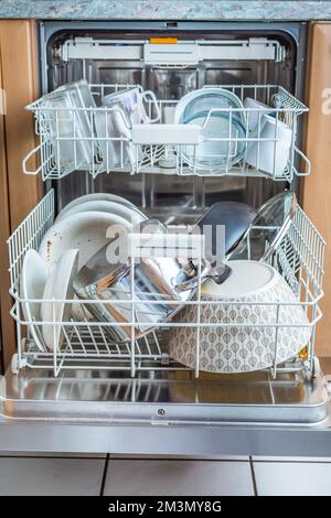 Offener moderner Geschirrspüler mit unordentlichem Geschirr in der Küche, eingebaute Küche Geschirrspülmaschine Stockfoto