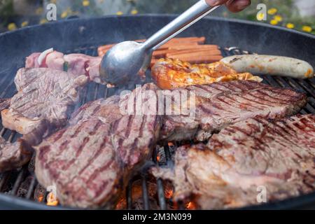 Steaks und Würstchen auf dem Holzkohlegrill Stockfoto