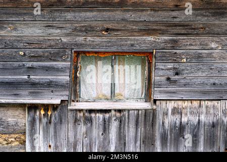 Ein kleines Fenster in einem alten Holzbadehaus im Dorf. Stockfoto