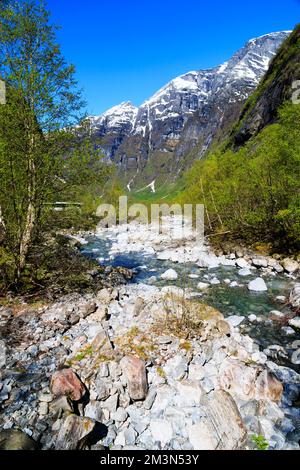 Klares Wasser aus Gletscherschmelzwasser vom Kjenndalsbreen-Gletscher vorbei an schneebedeckten Bergen im Lovatnet-Tal. Alt, Norwegen Stockfoto