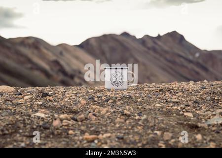 Nahaufnahme des emaillierten Bechers auf dem Konzeptfoto aus Kieselstein Stockfoto