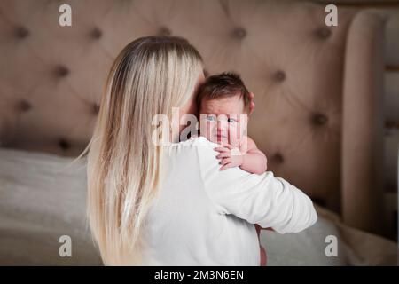 Mom hält verängstigtes, weinendes Neugeborenes in ihren Armen, beruhigt ihn Stockfoto