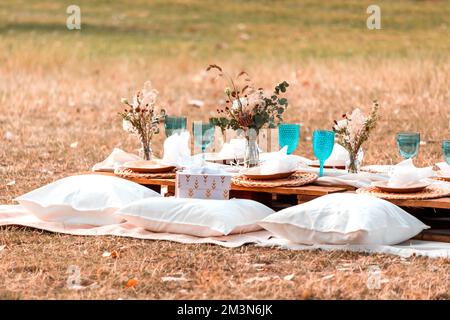 Dekorationen zum Fotografieren einer Hochzeit oder einer Party im Park mit Brille, Sitzkissen und Blumen. Romantisches Date Stockfoto
