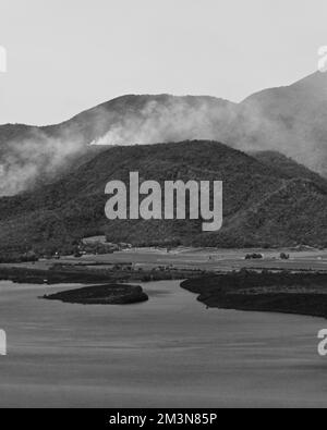 335BW Mündung des Mowbray River fließt in die Trinity Bay mit einem Hintergrund aus rauchbedeckten Bergen. Mowbray-Australien. Stockfoto