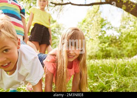 Porträt von lächelnden männlichen und weiblichen Freunden, die während des Schubkarrenrenrennen im Park gegeneinander antreten Stockfoto