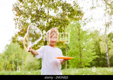 Sorgenfreier Junge, der während der Sommerferien im Garten Seifenblase macht Stockfoto
