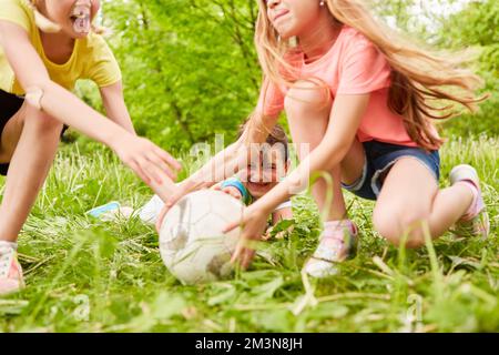 Mädchen, die mit einem männlichen Freund während des Wettkampfs im Park Fußball spielen Stockfoto