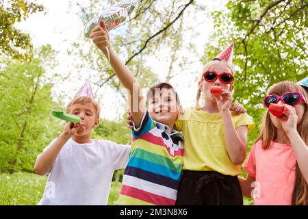 Fröhliche multirassische Kinder, die im Sommer gemeinsam im Garten ihre Geburtstagsparty feiern Stockfoto