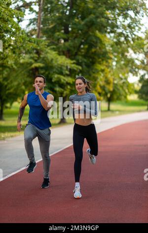 Ein junges Paar joggt zusammen auf einer roten Sportstrecke Stockfoto