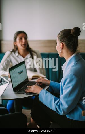 Geschäftsfrau, die am Laptop arbeitet und mit ihren Freunden über ihr neuestes Projekt chattet Stockfoto