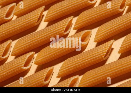 Rohe Teigwaren aus Vollweizenmehl auf beigefarbenem Hintergrund. Muster. Textur Stockfoto