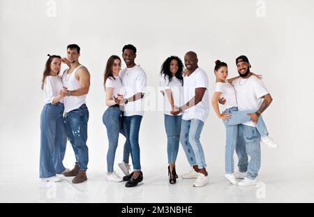 Eine Gruppe junger, glücklicher, multiethnischer Paare, isoliert auf weißem Hintergrund, die in die Kamera schauen und lächeln, weiße T-Shirts und Jeans tragen Stockfoto