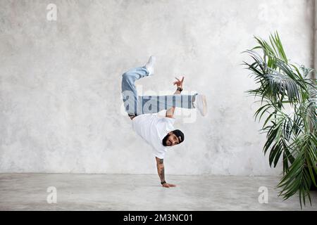 B-Boy macht einhändiges Einfrieren. Guy Breakdancer steht auf dem Arm und hob die Beine hoch. Hip-Hop-Tanz Stockfoto