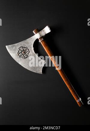 Antike mittelalterliche alte Axt mit Holzgriff isoliert auf schwarzem Hintergrund. Stockfoto