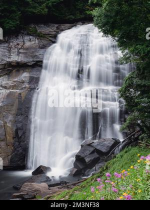 Ein wunderschöner seidiger Wasserfall fließt über Felsen und in den Fluss darunter Stockfoto