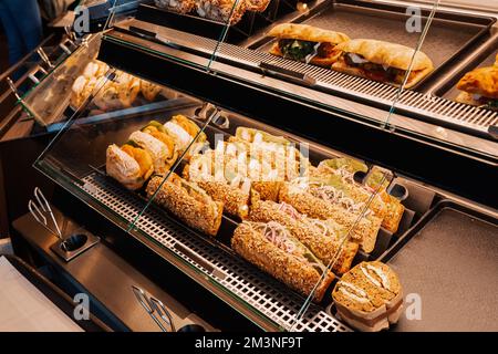 Eine Auswahl an Sandwiches mit verschiedenen Füllungen werden im Schaufenster eines Ladens oder Supermarkts verkauft. Snacks und Fast-Food-Konzept Stockfoto