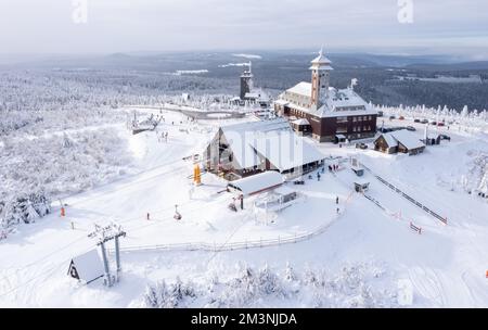 Oberwiesenthal, Deutschland. 16.. Dezember 2022. Als Winterlandschaft präsentiert sich der Gipfel des Fichtelbergs mit dem Fichtelberghaus. Im größten alpinen Skigebiet Sachsens am Fichtelberg beginnt die Saison am selben Tag. Vor allem der Frost der letzten Nächte hatte den Betreibern der Fichtelberg-Seilbahn in die Karten gespielt. So könnte man ausreichend künstlichen Schnee mit 70 Schneekanonen herstellen. Die ersten Langlaufstrecken sind ebenfalls in Betrieb. Kredit: Jan Woitas/dpa/Alamy Live News Stockfoto