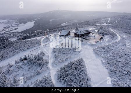 Oberwiesenthal, Deutschland. 16.. Dezember 2022. Als Winterlandschaft präsentiert sich der Gipfel des Fichtelbergs mit dem Fichtelberghaus. Im größten alpinen Skigebiet Sachsens am Fichtelberg beginnt die Saison am selben Tag. Vor allem der Frost der letzten Nächte hatte den Betreibern der Fichtelberg-Seilbahn in die Karten gespielt. So könnte man ausreichend künstlichen Schnee mit 70 Schneekanonen herstellen. Die ersten Langlaufstrecken sind ebenfalls in Betrieb. Kredit: Jan Woitas/dpa/Alamy Live News Stockfoto