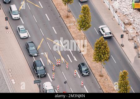 Luftaufnahme der Fahrbahnmarkierungen mit Pfeilen, die die Fahrspuren zum Wenden von Autos regeln, aufgrund einer provisorischen Baustelle vor uns Stockfoto