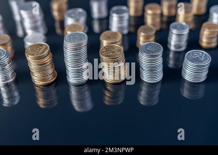 Stapel von Münzen (Polish Zloty, Grosze, PLN) auf einer schwarzen, reflektierenden Oberfläche. Inflation verschlingt unsere Ersparnisse. Schwierige Wirtschaftslage in Polen. Stockfoto