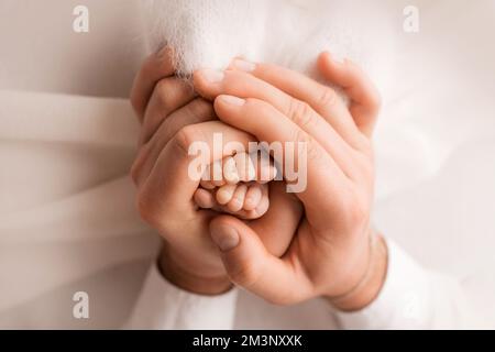 Die Füße der Kinder in den Händen von Mutter und Vater. Mutter, Vater und Kind. Stockfoto