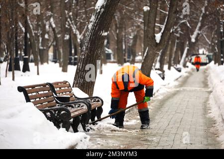 Arbeiter, der nach Schneefall auf der Straße der Stadt Schnee putzt. Mann mit Schaufel im Winterpark Stockfoto