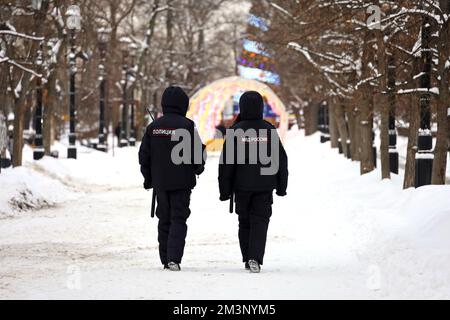 Russische Polizisten patrouillieren eine Straße in Moskau, vor dem Hintergrund von Neujahrsdekorationen. Übersetzung der Inschriften auf dem menschlichen Rücken: "Polizei" Stockfoto