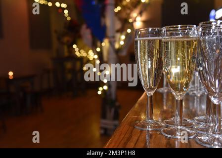 Sekt in Sektflöten an einer Bar mit sanften Lichtern im Hintergrund und Platz für Kopien Stockfoto