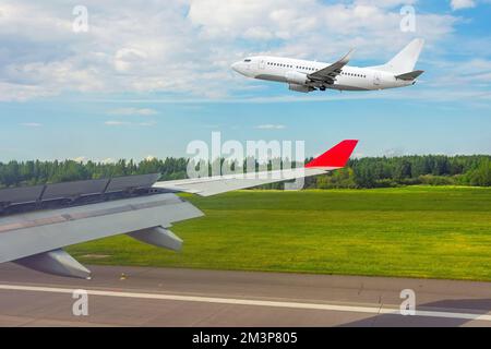 Sicht aus dem Fenster des Flugzeugs nach der Landung auf der Piste und einem parallel zur Seite abfliegenden Flugzeug Stockfoto